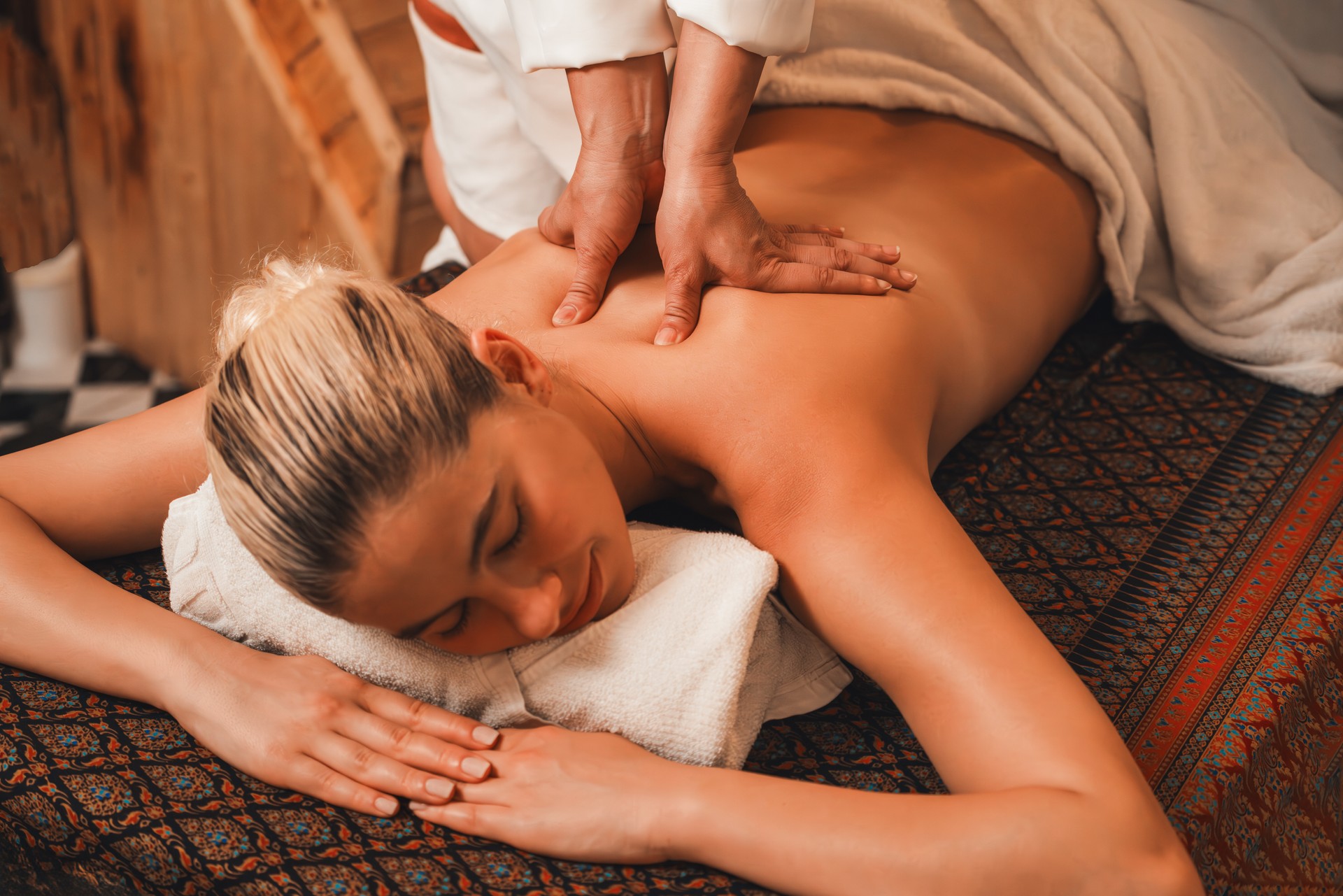 Attractive caucasian woman having back massage at warm sauna room. Tranquility.